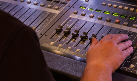 A sound engineer is adjusting the levels on this audio board during a live production.